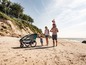 Eine Familie spaziert am Strand mit einem Qeridoo Kinderwagen.