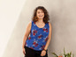 Eine Frau trägt ein blaues, blumiges Top ohne Ärmel und eine schwarze Hose.