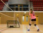 Eine Frau in einem rosafarbenen Shirt mit der Nummer 20 trainiert Volleyball mit einem Volleyballnetz und einem Trainingsziel.