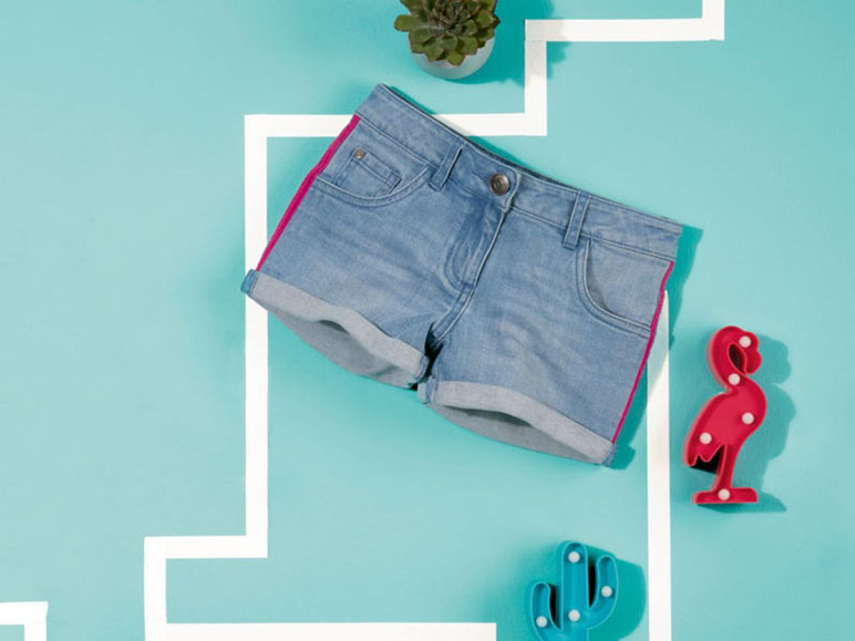 Eine Jeans-Shorts mit pinken Akzenten, eine Flamingo-Lampe und eine Kaktus-Lampe.