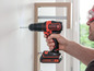 Ein Mann verwendet einen Black+Decker Akku-Bohrschrauber, um ein Regal an die Wand zu montieren.