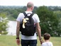 Ein Mann mit einem BackTrack-Rucksack und einem Plüschtier geht mit seinem Sohn spazieren.