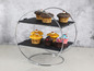 Ein runder Etagere mit zwei schwarzen Platten, gefüllt mit Cupcakes.