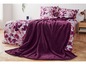 Eine dunkelviolette Decke auf einem Bett mit rosafarbenem Bettwäsche mit Blumenmuster.