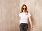 Eine Frau in einem weißen T-Shirt und Jeans trägt eine Sonnenbrille.