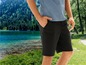 Schwarze Shorts für Herren, getragen von einem Model in einer Naturlandschaft.