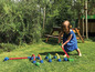 Ein Kind spielt Krocket im Garten mit bunten Toren und einem Schläger.