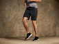 Mann in schwarzen Sport-Shorts und Sneakers beim Training.