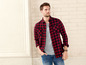 Mann mit rot-schwarzem kariertem Hemd, grauem T-Shirt und blauer Jeans.