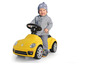 Ein Kind fährt auf einem gelben Volkswagen Beetle Lauflernwagen.
