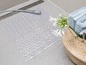 Eine transparente Badezimmermatte mit Rautenmuster in einem Badezimmer.