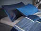 Blaue Bettwäsche mit Streifenmuster.