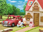 Ein rotes Spielzeugauto, ein Haus und Kaninchenfiguren von Sylvanian Families.