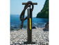 Eine schwarze Handpumpe von Hydro-Force für aufblasbare Wassersportartikel an einem Kiesstrand.