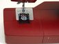 Eine rote Nähmaschine mit sichtbarem Spulenhalter.