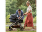 Ein Paar spaziert mit einem Mima Xari Kinderwagen im Park.