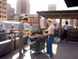 Eine Gruppe Freunde grillt auf einer Dachterrasse mit einem Weber Gasgrill.