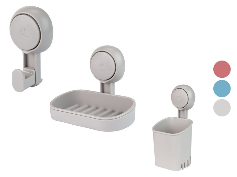 Drei graue Badezimmerzubehörteile mit Saugnapf: ein Seifenspender, ein Halter und ein Haken.