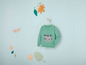 Ein grüner Pullover mit Katzenmotiv für Babys.