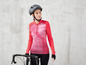 Eine Frau in einem rosa Fahrradtrikot und Helm steht neben einem Rennrad.