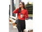 Eine Frau in einem roten Pullover und einem schwarzen Rock mit einer Tasse Kaffee.