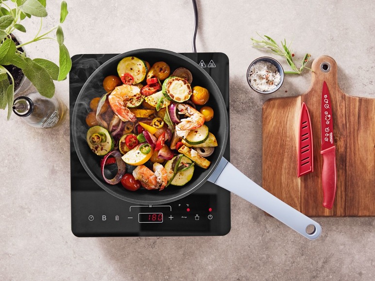 Eine Pfanne mit gebratenen Garnelen, Gemüse und einem Elektrokochfeld.