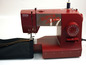 Eine rote Toyota Super Jeans Nähmaschine näht einen dunkelblauen Stoff.
