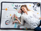 Eine Mutter und ein Baby spielen auf einer Tiny Love Spielmatte mit Tiermotiven.