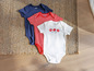 Lupilu Baby-Bodys in Weiß, Rot und Dunkelblau.