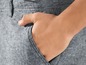 Eine Hand in der Tasche einer grauen Hose.