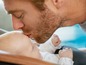 Ein Mann küsst ein Baby auf die Stirn.