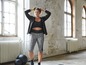Eine Frau in einem schwarzen Sport-BH und Leggings mit Muster in einem Fitnessstudio.