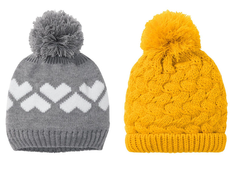 Zwei gestrickte Mützen mit Bommel, eine graue mit weißen Herzen und eine gelbe mit Zopfmuster.