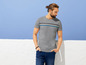 Ein Mann in einem grauen T-Shirt mit Streifen und blauen Jeans.