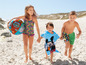 Kinder am Strand mit Paw Patrol Schwimm-Ball, Mickey Mouse Bademantel und Badebekleidung.