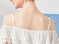 Eine Frau trägt ein weißes Oberteil mit Off-Shoulder-Stil und Spitzendetails.