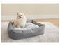Ein kleiner Hund in einem grauen Hundebett.