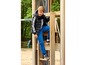 Ein Junge in einer schwarzen Steppjacke mit weißem Schriftzug und blauen Jogginghosen auf einem Spielplatz.