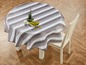 Ein runder Tisch mit einer gestreiften Tischdecke und einem weißen Stuhl.