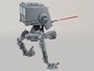 Ein graues Star Wars AT-ST-Modell mit rotem Laserstrahl.