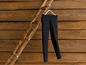 Schwarze Leggings hängen an einer Holzleiter vor einem Holz Hintergrund.