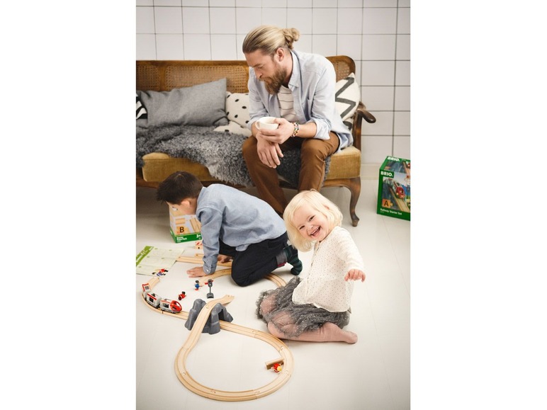 Zwei Kinder spielen mit einer Brio Eisenbahn.