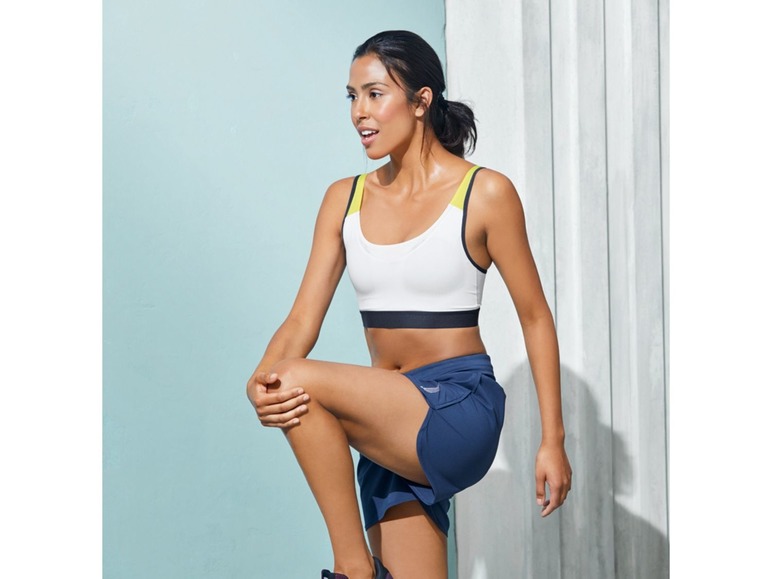 Eine Frau in Sport-BH und Shorts dehnt sich vor dem Training.