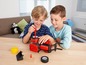 Zwei Jungen spielen mit einem roten Spielzeugtraktor und Zubehör.