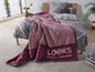 Eine rosa und violette Decke von Looks by Wolfgang Joop auf einem Bett.