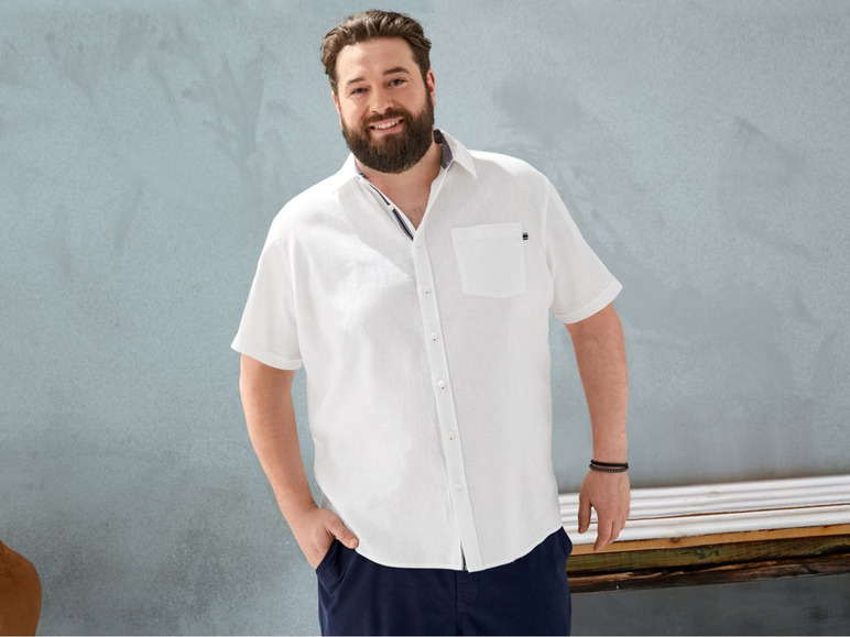 Ein Mann in einem weißen Hemd mit kurzen Ärmeln.