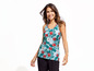 Eine Frau trägt ein Tanktop mit Blumenmuster und schwarze Hosen.