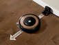 Ein Roomba-Roboterstaubsauger bewegt sich über einen Holzboden zu seiner Ladestation.