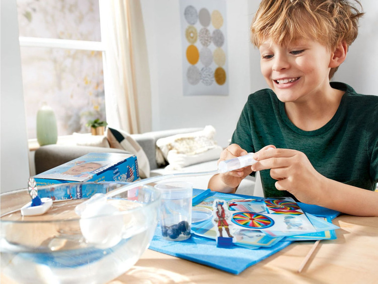 Ein Junge spielt mit einem Wissenschaftsset, das ein Boot, eine Windmühle und andere Materialien beinhaltet.