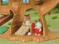 Ein Calico Critters Baumhaus mit einer Rutsche und zwei Puppen.